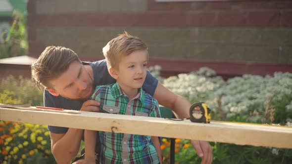 Male Carpenter with His Son Working Outside Near the House