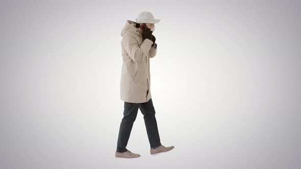 Man Wears Protective Medical Mask and Talks on the Phone Walking on Gradient Background.