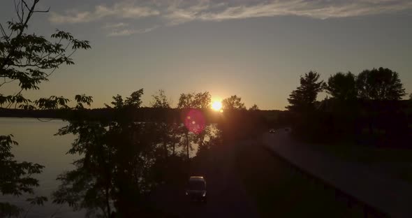 Flying Up Over Road Along Lake At Sunset in New England