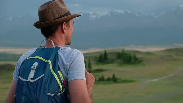 Adult traveler walks through hills of mountain valley with a backpack