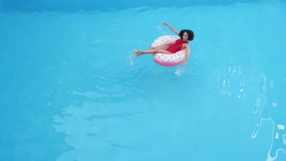 A Young Swimmer Teenage Girl Sits in Inflatable Life-saving Circle Inblue Clean Cool Water in Sea