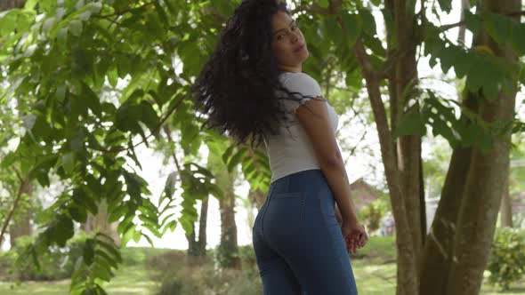 Young sexy latina in blue jeans looking over her shoulder in a sunny park