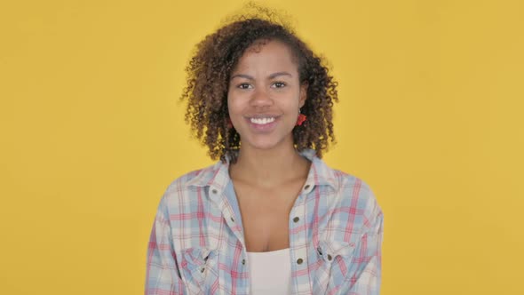Young African Woman Smiling at Camera on Yellow Background