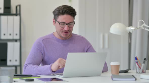 Video Chat on Laptop By Middle Aged Man in Office