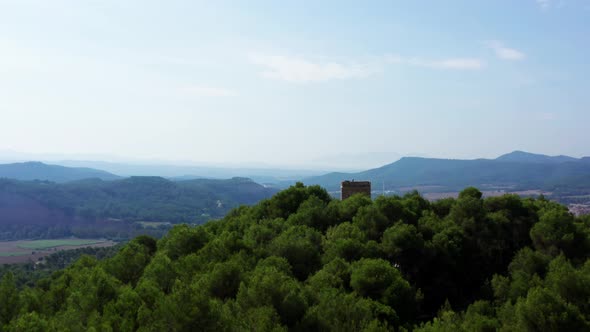 Drone flies past a Historic European Watchtower Perched on a Mountain top revealing an Epic Rural Sp