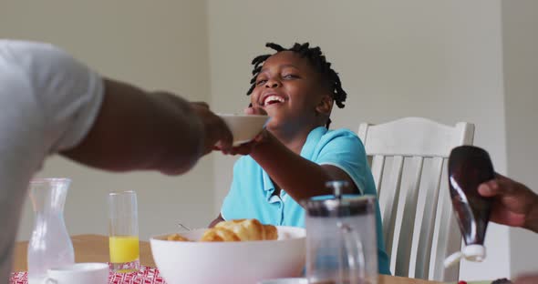 African american boy smiling while having breakfast together with his family at home