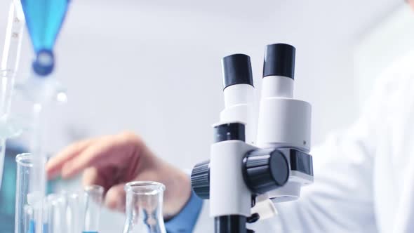 Low Angle Shot of Chemist Analyzing Tubes with Samples Then Looking in Microscope