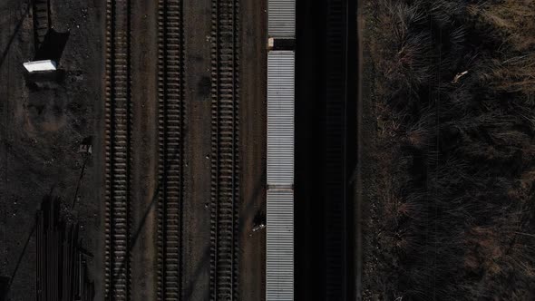 Aerial View of a Large Train on the Rails Next To the River. The Camera Flies Over a Long Train of