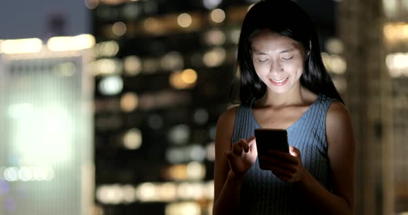 Business woman using smart phone in the city at night 