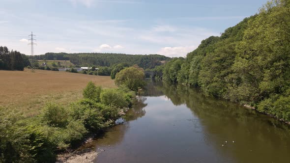 Brown fields and lush deciduous forests growing along the shore of the Sieg river in west Germany. W