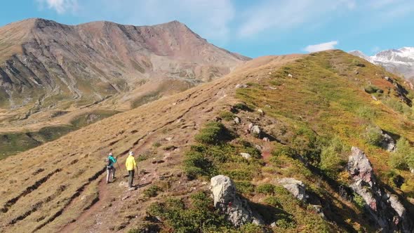 Two Unidentified Tourists with Backpacks Hiking in Caucasus Mountains in Georgia