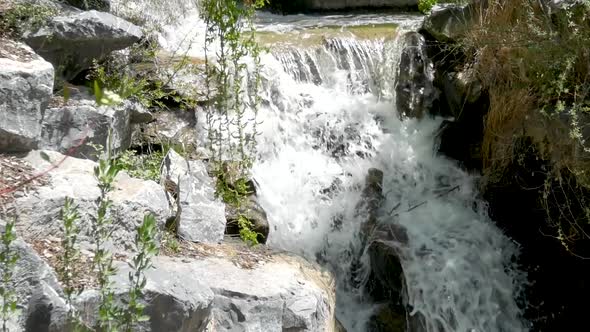 Very close static shot of a river cascading down rocks in a small waterfall in the forest