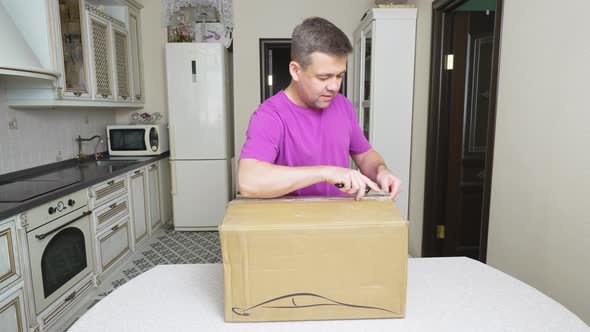 a Man Opens a Box with an Electric Car Charger