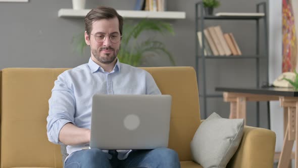 Young Man Working on Laptop on Sofa