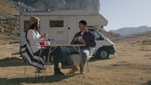 At Rv People at Table Have Dinner and Smile Against Background of Mountain Rbbro