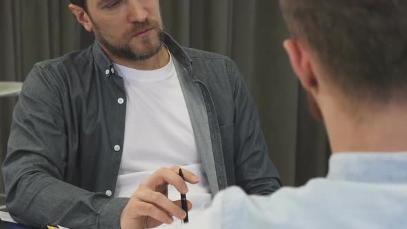 Cropped Shot of a Mature Businessman Listening Attentively To His Colleague at the Meeting