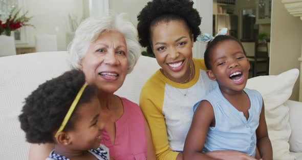 Portrait of happy african american grandmother with adult daughter and granddaughters in living room