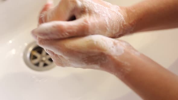 Woman Washes Her Hands in the Bathroom with Water Soap and Foam