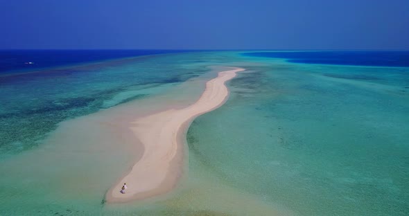 Daytime aerial tourism shot of a sunshine white sandy paradise beach and aqua blue ocean background 