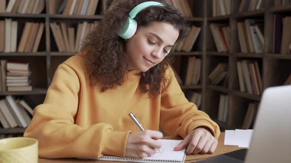 Hispanic Teen Girl Student Wear Headphones Watching Webinar Class Making Notes