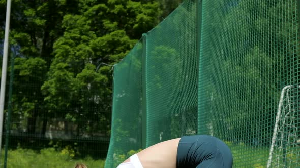 Young Sporty Blond Girl in Sportswear Does Exercises Outdoors at Sports Ground