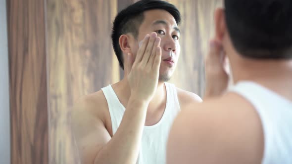 Young Asian Man Applying Skincare Cream in Bathroom