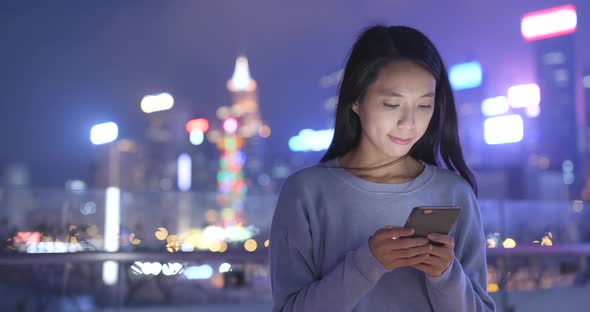 Woman look at smart phone in the city at night