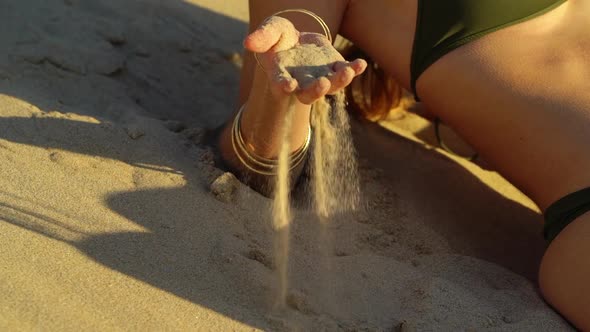 View of a Female's Body and Hand Playing with White Sand on the Beach