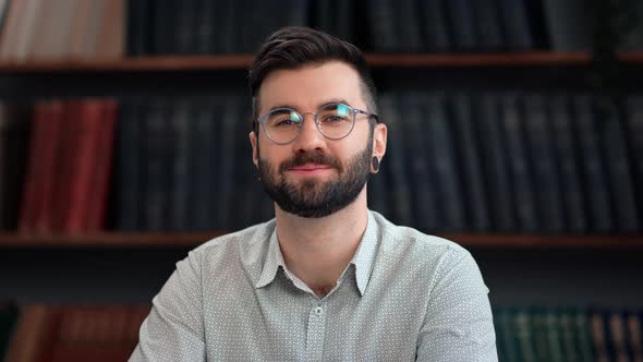 Portrait Smiling Trendy Bearded Man in Shirt Posing at Library Bookshelves Interior Positive Emotion
