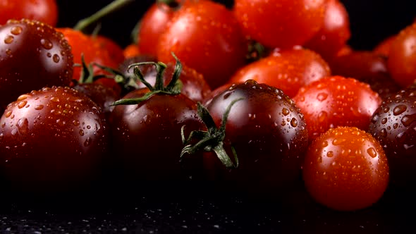 Cherry tomatoes on a black background in water drops.