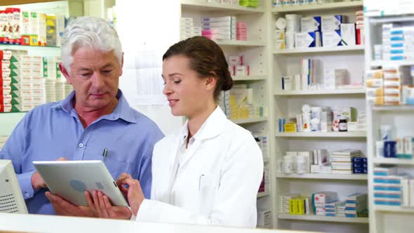 Pharmacists using digital tablet at counter