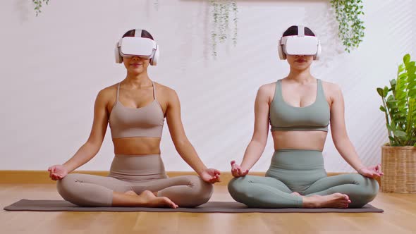 Couple Asian young woman sit on yoga mat wear virtual reality glasses doing breathing exercise yoga