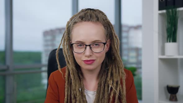 Woman with Dreadlocks in Glasses Posing on Camera with Sincerely Smile in Modern Office