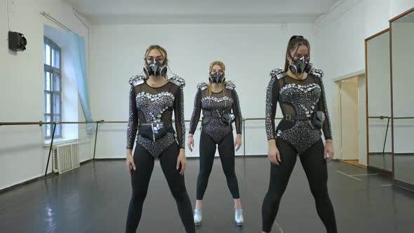 Zoom in to Three Confident Talented Female Extravagant Dancers Standing in Costumes in Studio Start