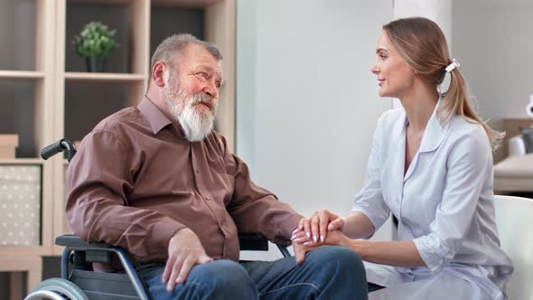 Happy Disabled Elderly Man Smiling Talking to Woman Doctor at Regular Medical Examination