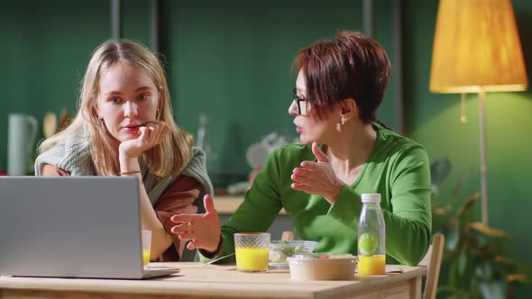 Two Women Having Lunch, Talking and Using Laptop at Home