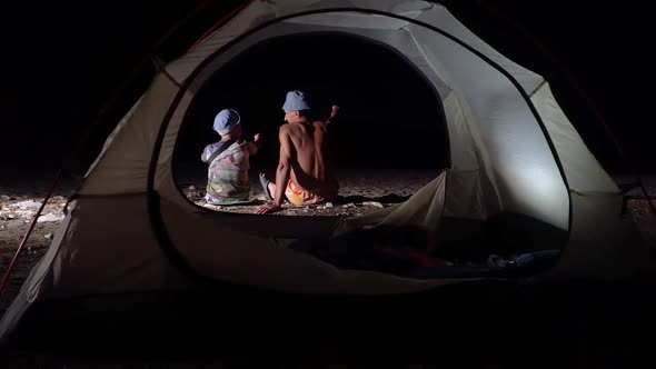 Son and Father Near the Tent at Night