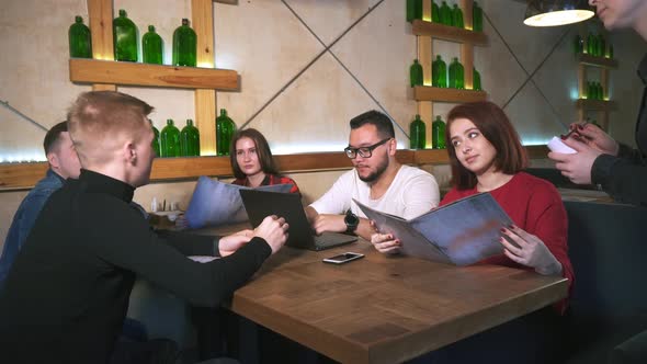 Waiter in Restaurant Takes Order From Group of Friends.