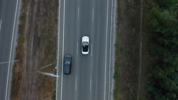 Aerial drone shot of a car driving on a bridge.