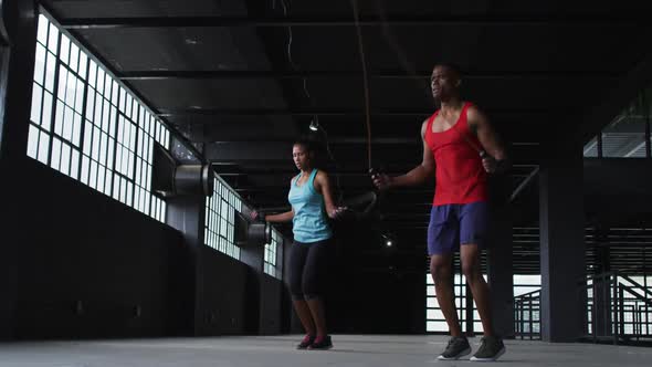 African american man and woman skipping rope in an empty urban building