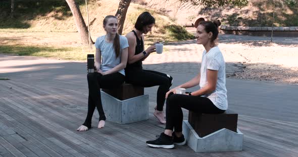 Three Girls Sit in the Park Before the Start of Training and Chat