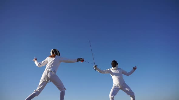 A man and woman fencing on the beach