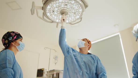 Professional Surgeons Turning on Surgery Lights While Bending Over Patient