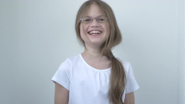 Child Girl in Glasses Laughing at Funny Joke Looking at Camera