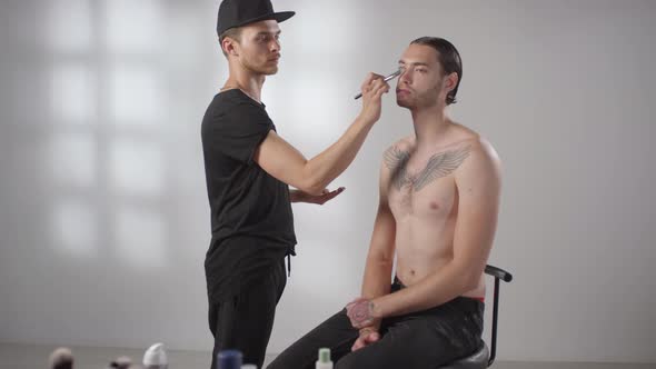 Make-Up Artist Applying Product on Face of Male Model