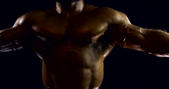 Close-up Portrait of a Male Naked Body of a Bodybuilder, He Is in the Studio on a Black Background