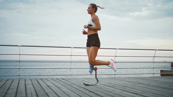 Young Woman with Prosthetic Running on Pier Near Sea