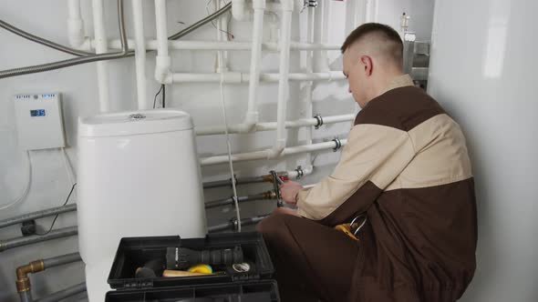 Handyman in Uniform Fixing Pipes in Bathroom