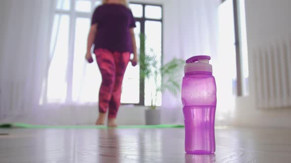 Fitness Training Overweight Woman Exercising with Little Dumbbells and Puts Them Down Takes a Bottle