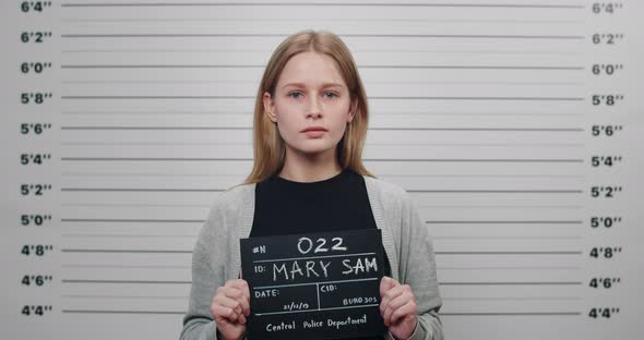 Mugshot of Attractive Arrested Woman Holding Sign for Photo in Police Department